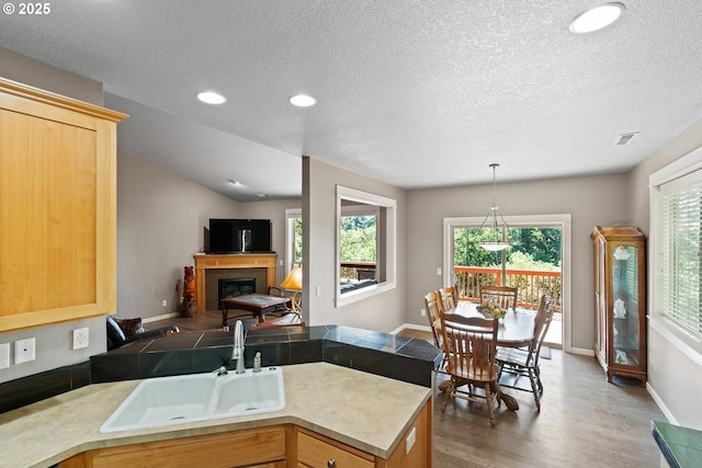 862 NW Edgewood Pl, Albany, OR 97321 - kitchen featuring a sink, wood finished floors, a textured ceiling, a tile fireplace, and open floor plan