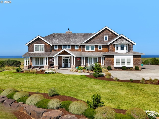view of front facade featuring covered porch, a chimney, and a front lawn
