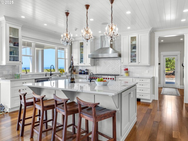 kitchen featuring wall chimney range hood, a chandelier, a sink, plenty of natural light, and recessed lighting