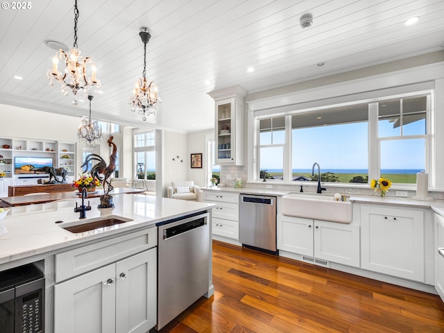kitchen with appliances with stainless steel finishes, a chandelier, a sink, ornamental molding, and open floor plan