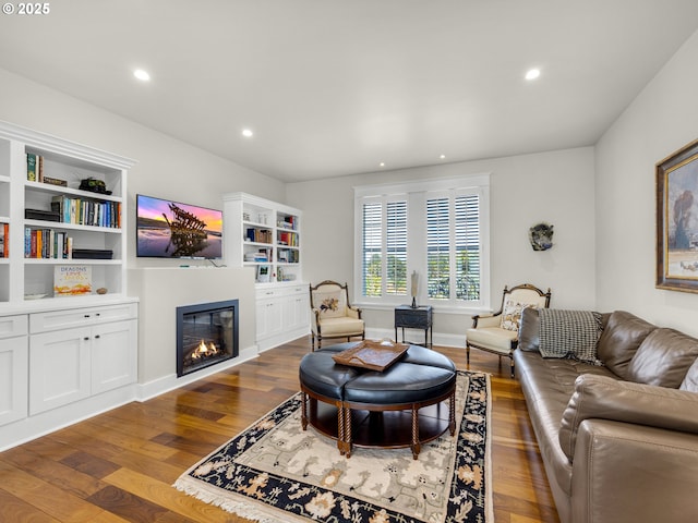 living room with dark wood finished floors, a glass covered fireplace, and recessed lighting