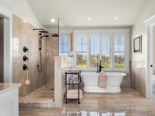 bathroom with a freestanding tub, walk in shower, recessed lighting, lofted ceiling, and tile walls