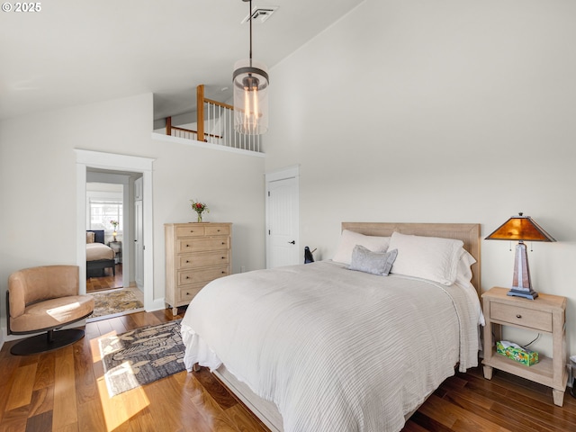 bedroom with high vaulted ceiling and wood finished floors