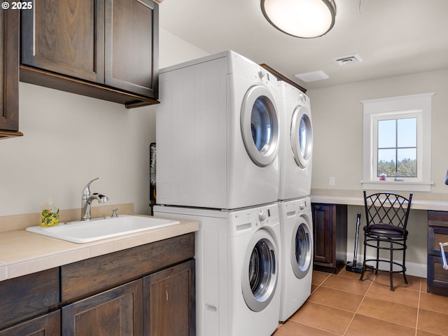 laundry area with cabinet space, stacked washer / drying machine, and light tile patterned floors