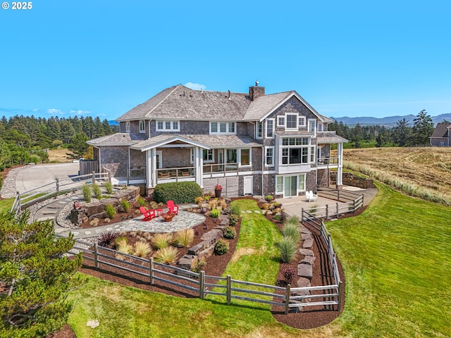 rear view of house featuring a patio area, a chimney, a balcony, and a mountain view