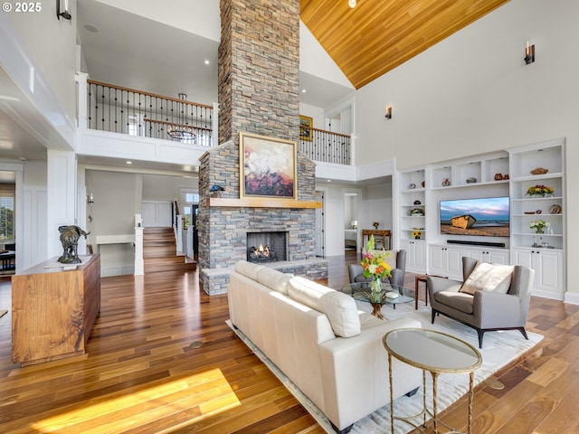 living area with high vaulted ceiling, a stone fireplace, wood finished floors, and wood ceiling