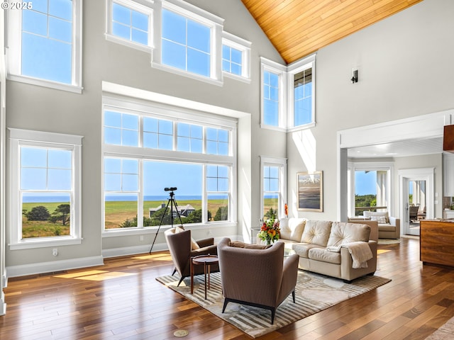 living room featuring high vaulted ceiling, hardwood / wood-style flooring, plenty of natural light, wooden ceiling, and baseboards