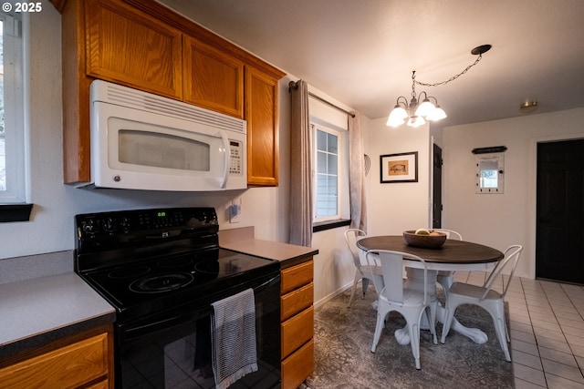 kitchen with decorative light fixtures, dark tile patterned floors, black electric range oven, and a chandelier