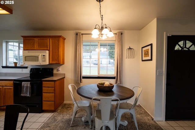 kitchen with light tile patterned floors, black electric range, hanging light fixtures, and a notable chandelier