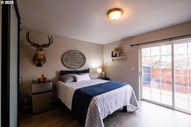 bedroom with access to exterior, dark hardwood / wood-style floors, and stainless steel refrigerator