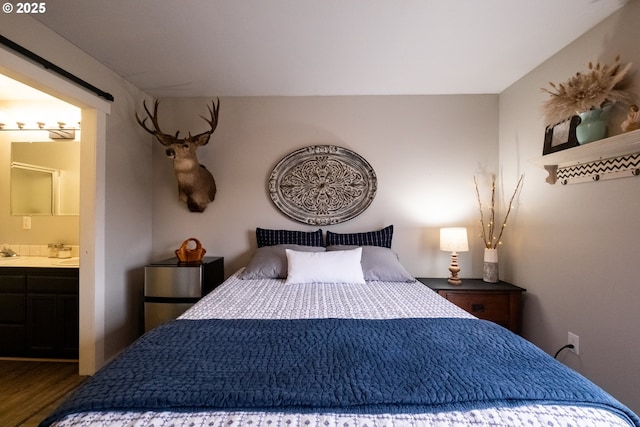 bedroom with dark wood-type flooring, sink, and ensuite bath