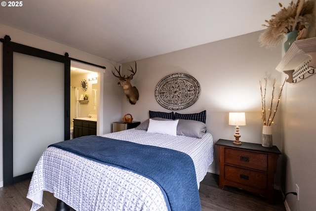 bedroom with ensuite bath, a barn door, and dark wood-type flooring