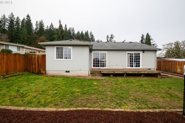 rear view of house with a wooden deck and a lawn