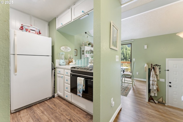 43605 State Highway 38 Unit 22, Reedsport, OR 97467 - kitchen featuring freestanding refrigerator, white cabinets, light wood-type flooring, gas range oven, and light countertops
