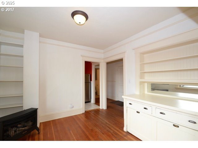 interior space with wood finished floors, white cabinetry, freestanding refrigerator, open shelves, and crown molding