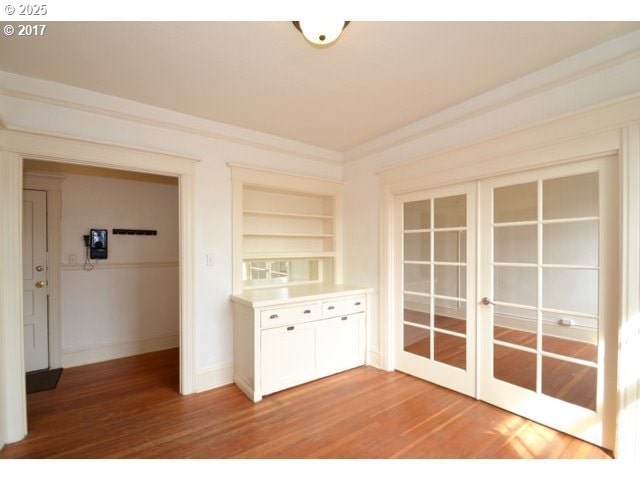 interior space featuring light countertops, crown molding, french doors, light wood-type flooring, and white cabinetry