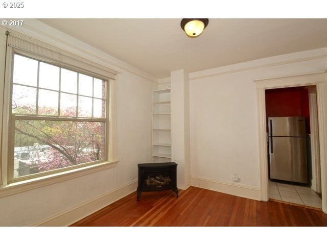 unfurnished room with ornamental molding, light wood-type flooring, and baseboards