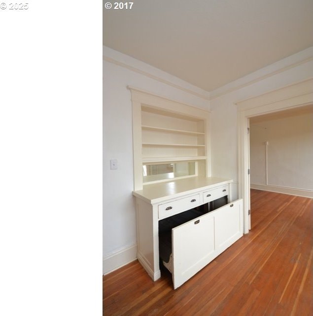 interior space featuring baseboards, crown molding, built in features, and wood finished floors