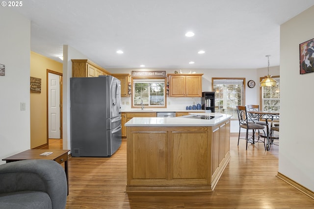 14504 SE Old Barn Ln, Damascus, OR 97089 - kitchen with appliances with stainless steel finishes, light wood-type flooring, light countertops, a kitchen island, and a sink