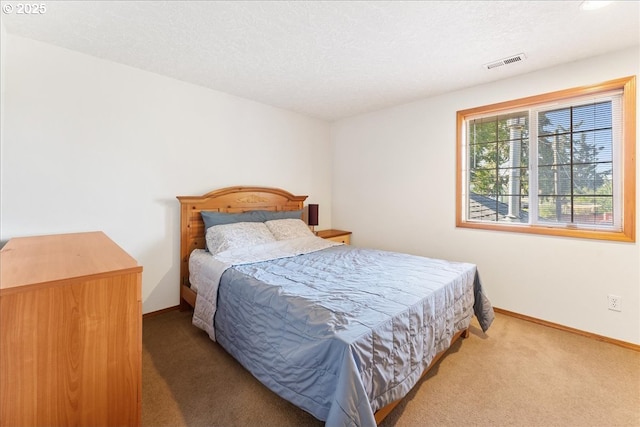 bedroom featuring a textured ceiling, carpet floors, visible vents, and baseboards