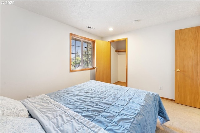 bedroom featuring a textured ceiling, baseboards, visible vents, and light colored carpet