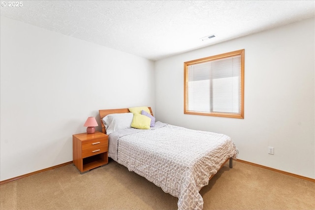 bedroom with baseboards, a textured ceiling, visible vents, and light colored carpet