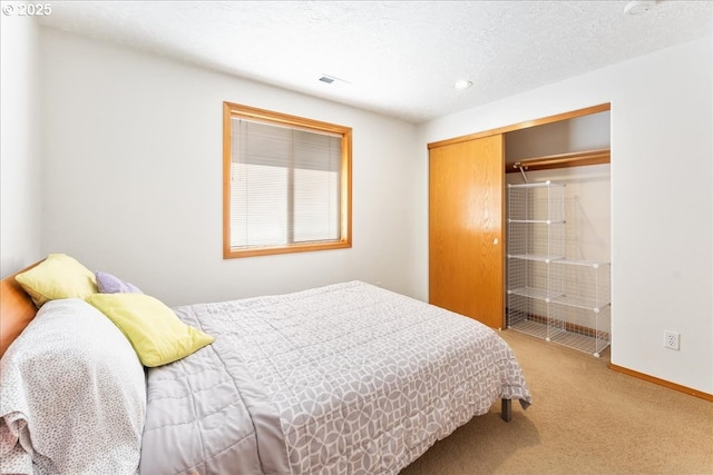 carpeted bedroom featuring baseboards, a closet, visible vents, and a textured ceiling