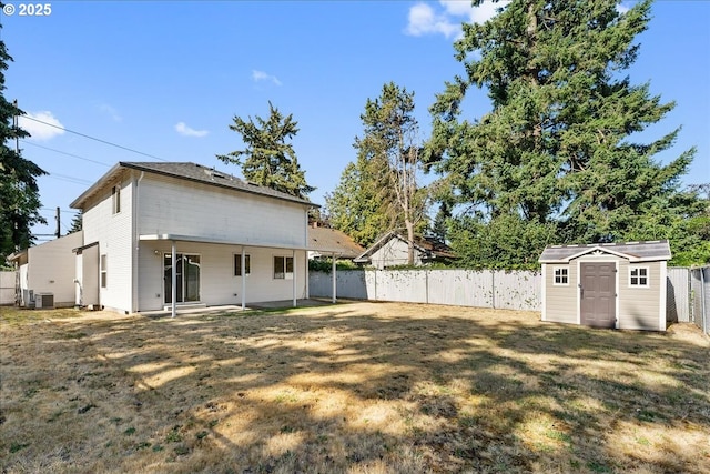 rear view of house featuring a storage unit, a lawn, cooling unit, a fenced backyard, and an outdoor structure