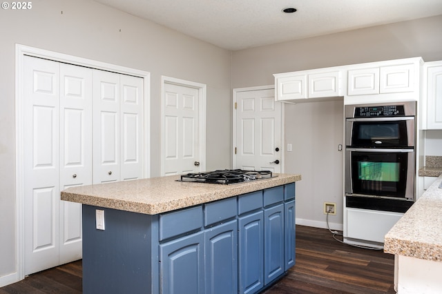 kitchen featuring white cabinets, stainless steel appliances, blue cabinets, and dark wood-type flooring