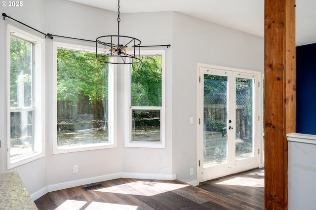 doorway to outside featuring an inviting chandelier, plenty of natural light, wood finished floors, and visible vents