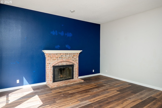 unfurnished living room with baseboards, a fireplace, and wood finished floors