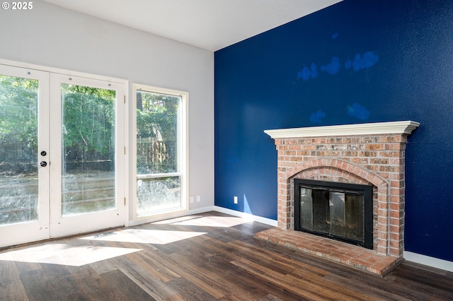 unfurnished living room with baseboards, a brick fireplace, and wood finished floors