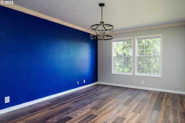 spare room featuring visible vents, ornamental molding, wood finished floors, baseboards, and a notable chandelier