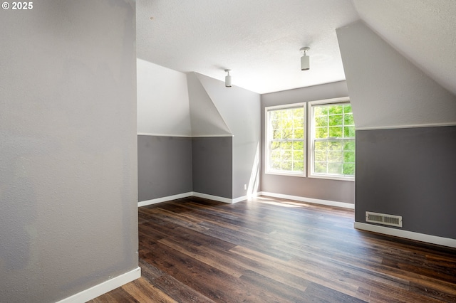 bonus room featuring baseboards, visible vents, wood finished floors, and lofted ceiling
