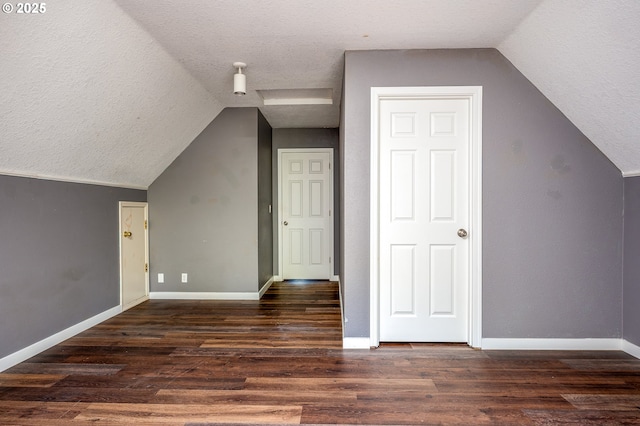 additional living space featuring a textured ceiling, baseboards, vaulted ceiling, and wood finished floors