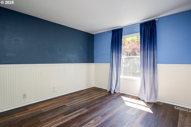 unfurnished room featuring wainscoting, wood finished floors, and visible vents