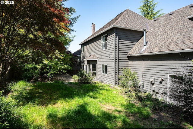 view of home's exterior with a chimney and roof with shingles