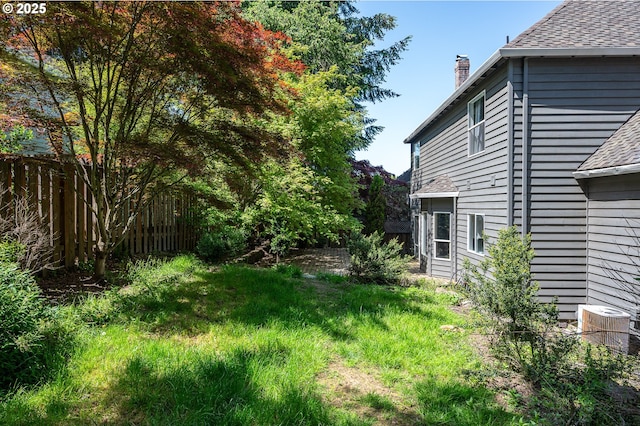 view of yard featuring central AC and fence