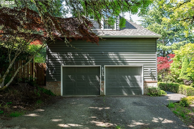 garage with fence and aphalt driveway