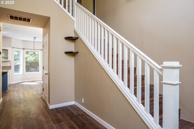 staircase featuring baseboards, visible vents, and wood finished floors