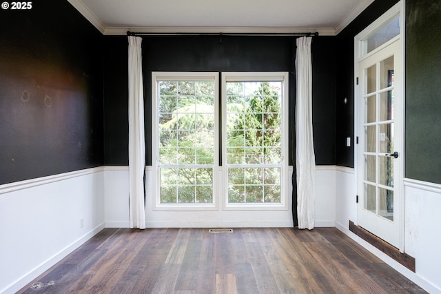 empty room with crown molding, visible vents, a healthy amount of sunlight, and wood finished floors