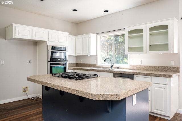kitchen with a kitchen island, white cabinetry, appliances with stainless steel finishes, and dark wood finished floors