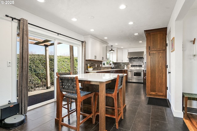 kitchen with range with two ovens, decorative backsplash, extractor fan, light countertops, and recessed lighting