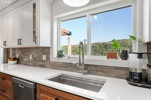 kitchen featuring glass insert cabinets, a sink, light countertops, white cabinetry, and stainless steel dishwasher