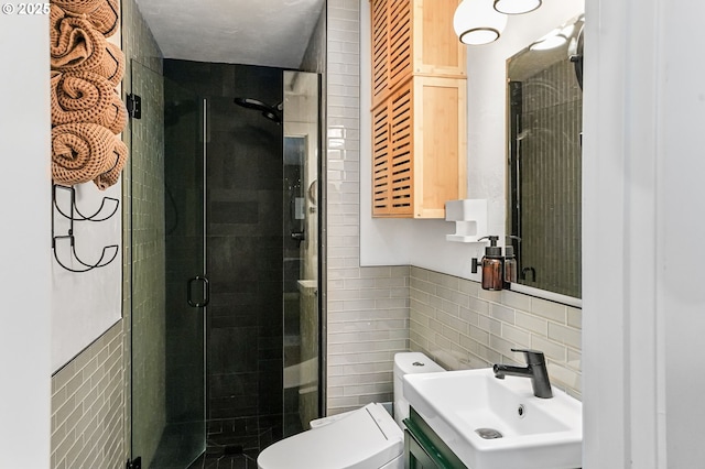 bathroom with tile walls, a shower stall, toilet, and vanity