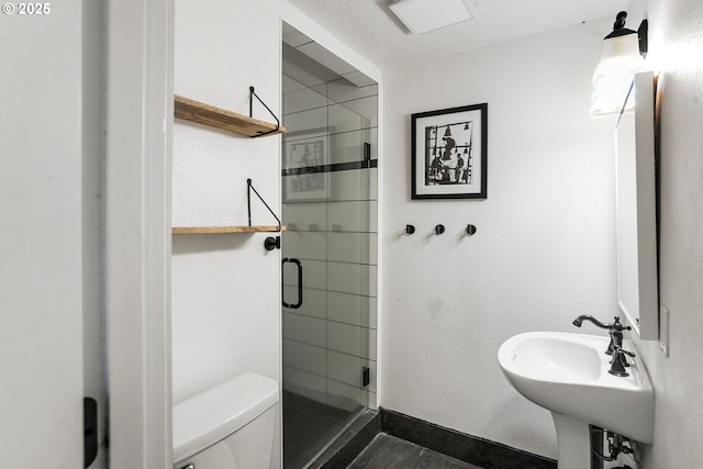 full bathroom with baseboards, toilet, a textured ceiling, a shower stall, and a sink