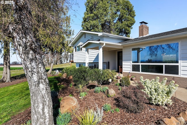 view of front facade with a chimney and a front lawn