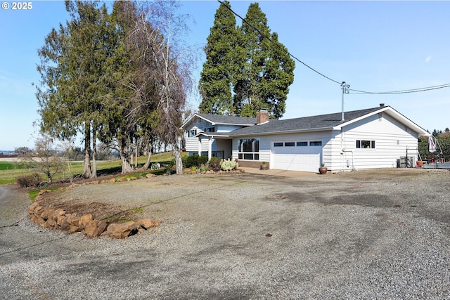 view of front of property featuring driveway, a chimney, and an attached garage