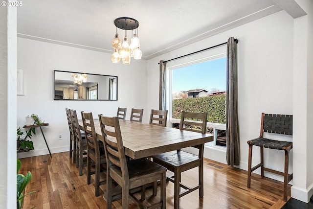 dining area with visible vents, baseboards, a notable chandelier, and wood finished floors