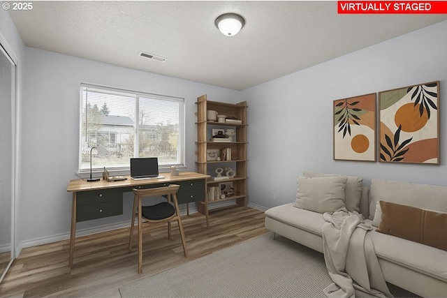 home office featuring a textured ceiling, wood finished floors, visible vents, and baseboards